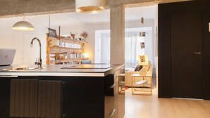 Et moderne køkken med en central ø, et spiseområde med en stol og en reol.