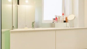 Et moderne badeværelse med en hvid kommode, et spejl og diverse toiletartikler.