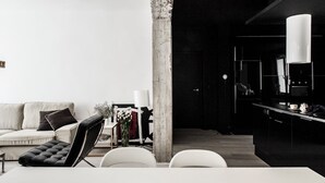 En moderne stue med sofa, stole, sofabord og et spiseområde med bord og stole.