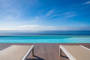A poolside area with two lounge chairs facing a clear blue ocean under a bright sky. - Spacious premium villa in Calheta | Ocean Panorama (Estreito da Calheta)