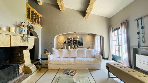 A living room with a white sofa, a glass coffee table, a fireplace, and a stone wall. - Gorgeous 4 bedroom, 3 bathroom villa with private pool & sea view in Mougins (Mougins)