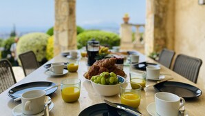 A breakfast table set with plates, cups, glasses, and a croissant, overlooking a scenic view. - Gorgeous 4 bedroom, 3 bathroom villa with private pool & sea view in Mougins (Mougins)