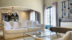 A spacious living room with a white sofa, a glass coffee table, and a beige armchair. - Gorgeous 4 bedroom, 3 bathroom villa with private pool & sea view in Mougins (Mougins)