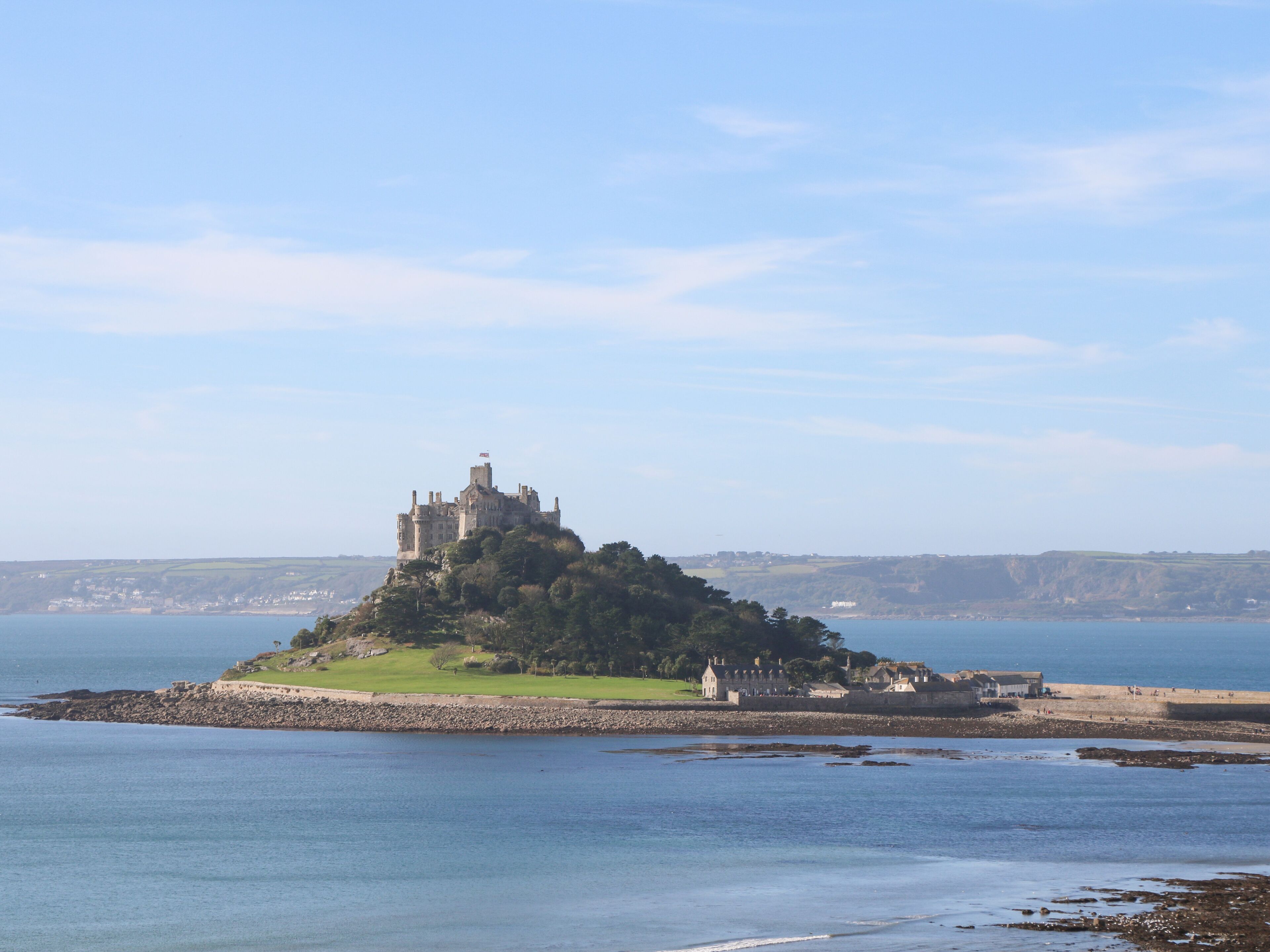 Un château situé sur une petite île, offrant une vue sur la mer et les collines lointaines.