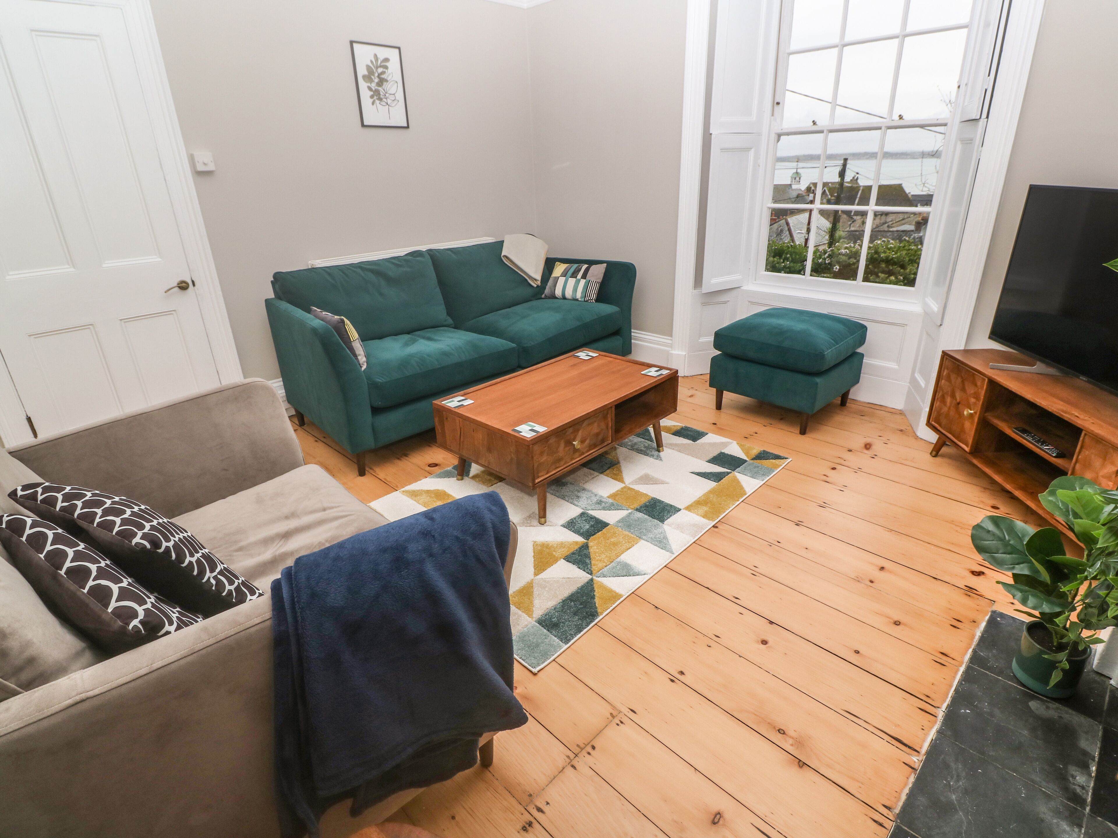 Een woonkamer met een groene bank, een houten salontafel en een tv-meubel.