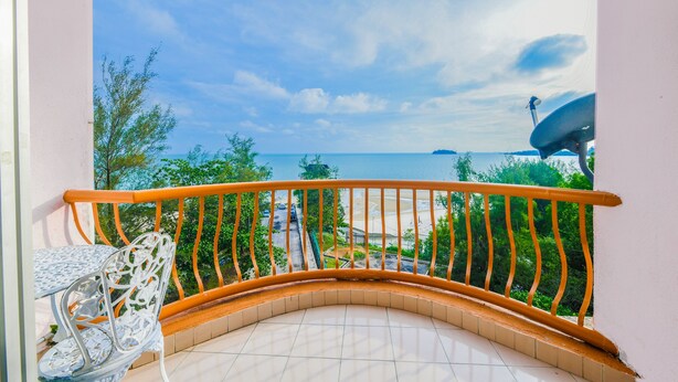 Un balcon doté d’une balustrade incurvée, d’une table et d’une chaise.