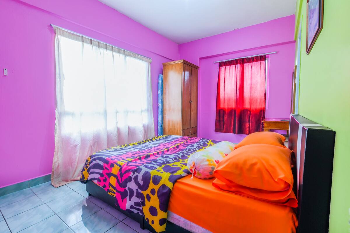 Ein Schlafzimmer mit Bett, Vorhängen, einem Kleiderschrank und einem Fenster.
