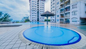 Un espace piscine agrémenté d’un kiosque, entouré d’immeubles d’habitation de grande hauteur.