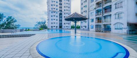 A swimming pool area with a gazebo, surrounded by high-rise residential buildings.