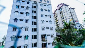 Un immeuble à plusieurs étages, doté de nombreuses fenêtres et de balcons, et entouré de verdure.