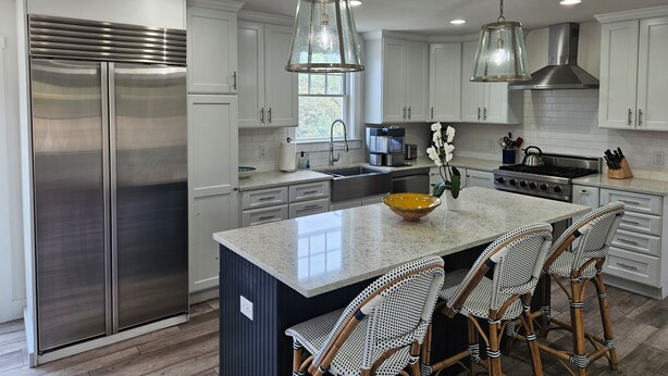 A modern kitchen with stainless steel appliances, white cabinetry, and a central island with bar stools. - Beautiful 4 bed with Pool + Spa (Nantucket)
