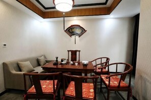 Un coin repas comprenant une table ronde, quatre chaises, un canapé et une décoration murale traditionnelle.