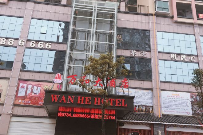 A hotel with a prominent sign, multiple windows, and a tree in front.