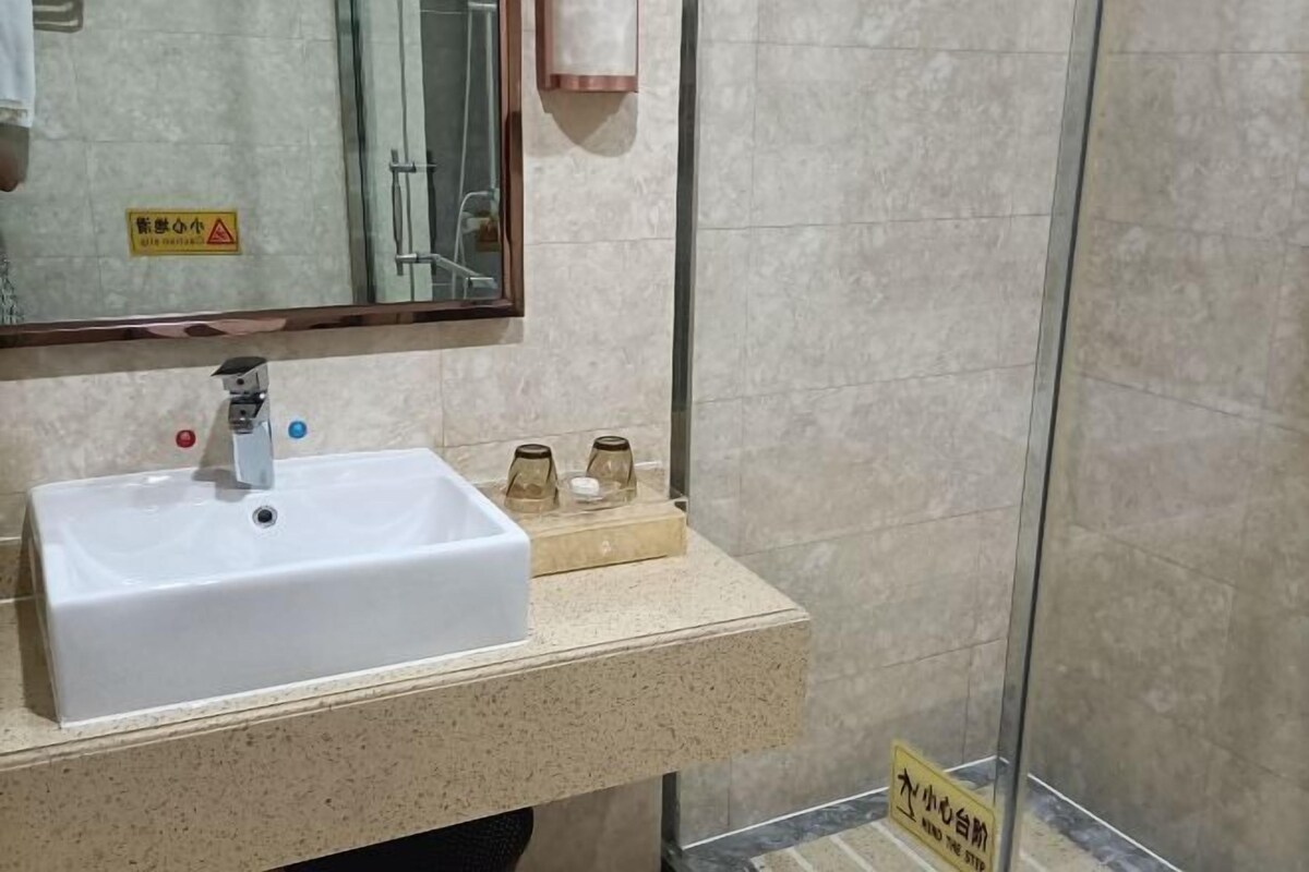 A bathroom with a white sink, a mirror, and a glass shower enclosure.