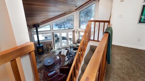 A cozy loft-style living area with a fireplace, a staircase, and large windows offering a view of the outdoors. - Hermosa Haven | Red Cliff Views, Garage, 30+ Stay (Durango)