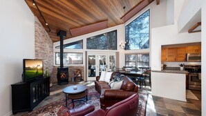 A spacious living area with a fireplace, leather sofas, a television, and a large window overlooking a snowy landscape. - Hermosa Haven | Red Cliff Views, Garage, 30+ Stay (Durango)