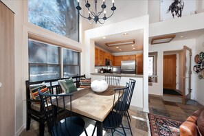 A spacious dining area with a wooden table and chairs, a chandelier, and a view of the outdoors through large windows. - Hermosa Haven | Red Cliff Views, Garage, 30+ Stay (Durango)