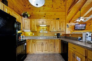 Enjoy cooking in this well-equipped kitchen with a central island, refrigerator, microwave, dishwasher, sink, and television.
