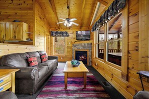 Relax in this inviting room with a leather sofa, stone fireplace, and large windows offering views of the surrounding landscape.