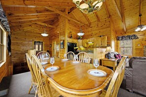 Cozy cabin-style room with a dining table for four, high ceiling, and a chandelier.