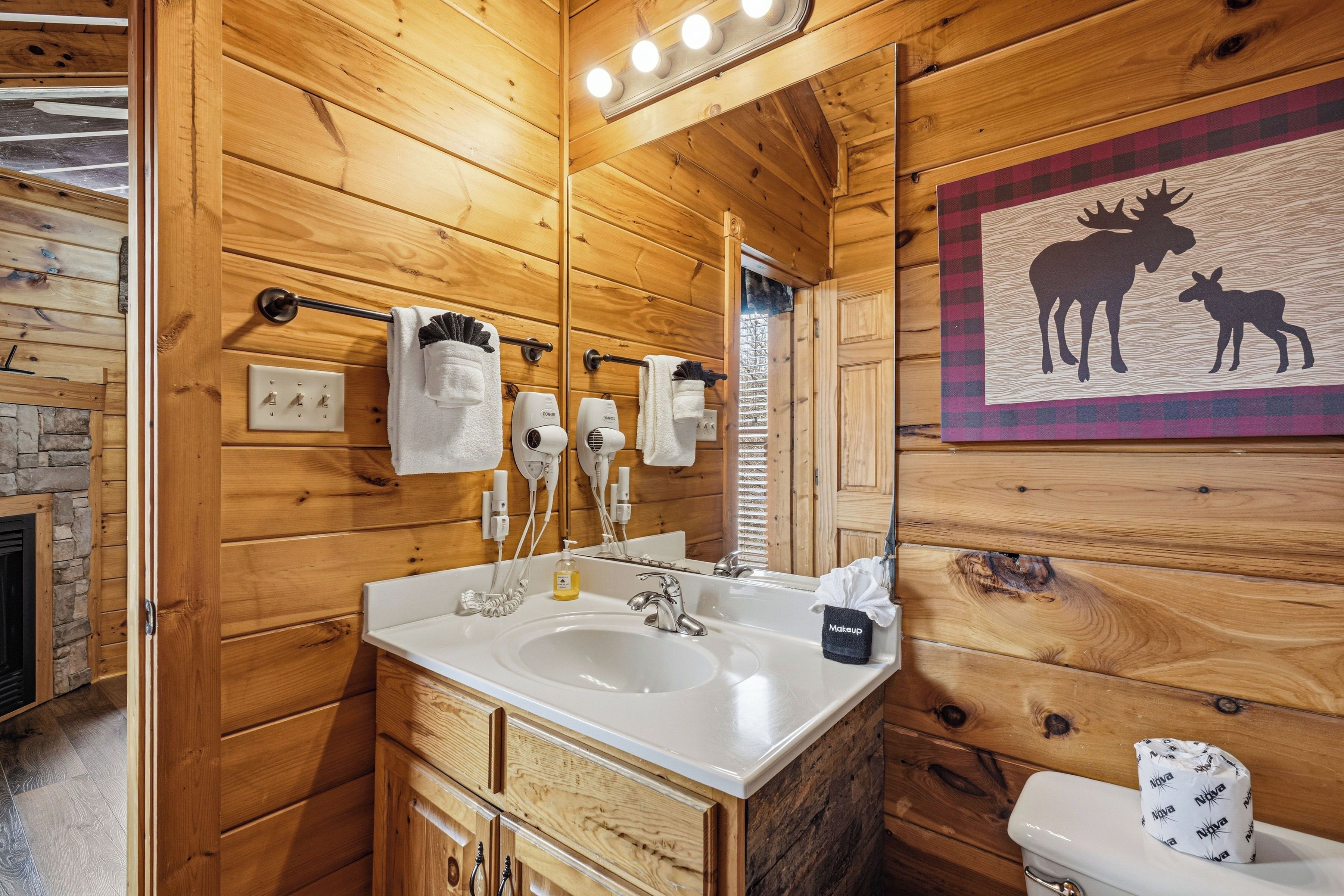 A wooden cabin bathroom with a sink, towel rack, and a mirror.