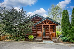 Surrounded by lush greenery, this cabin features a charming front porch and a well-maintained garden.