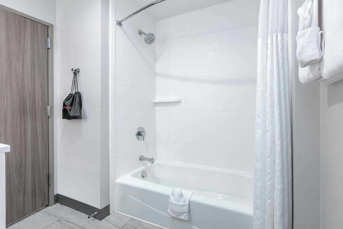 Ein modernes Badezimmer mit einer weißen Badewanne, einer Duschbrause und einem Handtuchhalter.