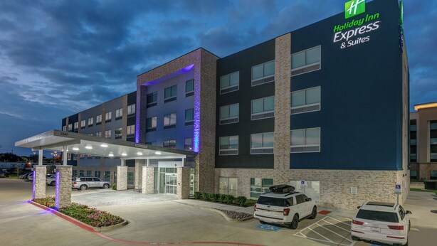 Un bâtiment Holiday Inn Express & Suites doté d’une entrée couverte, d’un parking et de places de stationnement accessibles aux personnes handicapées.