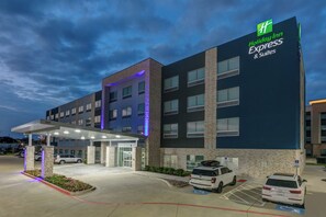 A Holiday Inn Express & Suites building with a covered entrance, parking lot, and handicap-accessible parking spaces.