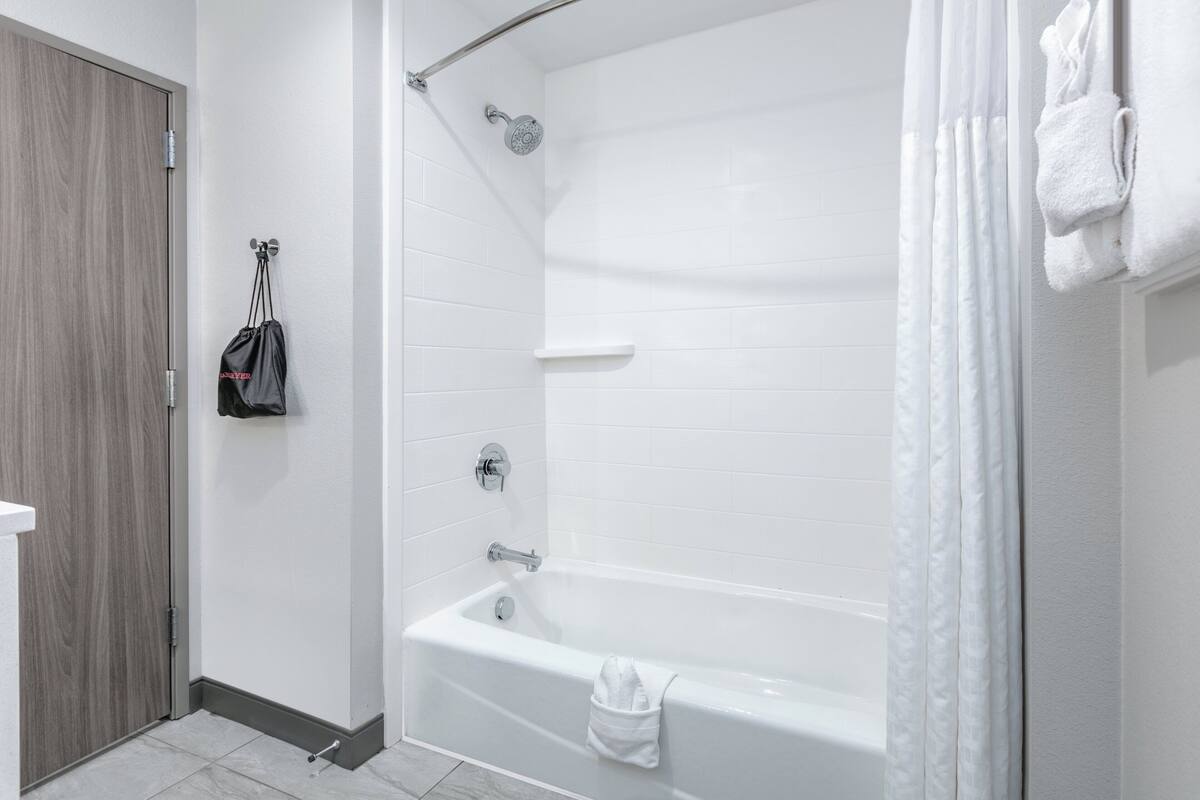 A modern bathroom with a white bathtub, a showerhead, and a towel rack.