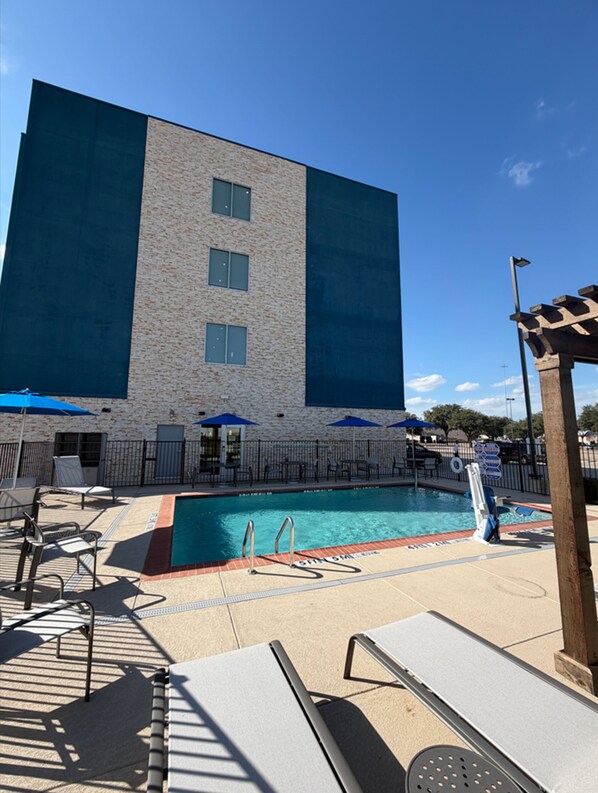 A hotel with a pool area, outdoor seating, and a large building facade. - Holiday Inn Express & Suites Dallas – Plano North by IHG (Plano)