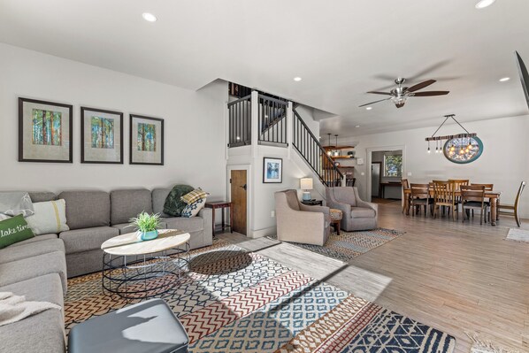A spacious living area with a staircase, a dining area, and a ceiling fan. - Fun Amok - Warren Wagon Rd - WiFi - Large driveway - Hot tub (McCall)