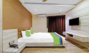 Una habitación de hotel moderna con cama, televisor, teléfono y ventana con cortinas.