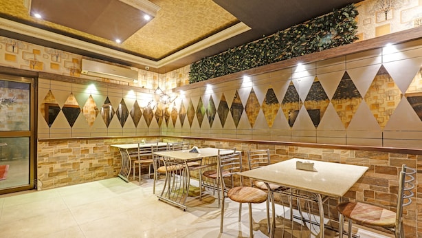 Un restaurant amb parets de pedra, un sostre amb motius i una filera de taules i cadires.