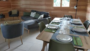 Et træinteriør med et spisebord dækket til fire personer, en sofa og en stol.