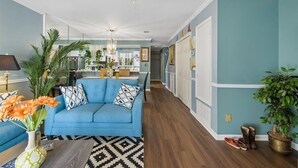 A living room with a blue sofa, a patterned rug, and a ceiling fan.