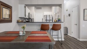 Une cuisine moderne avec des meubles blancs, des appareils en acier inoxydable et un îlot central doté de tabourets.