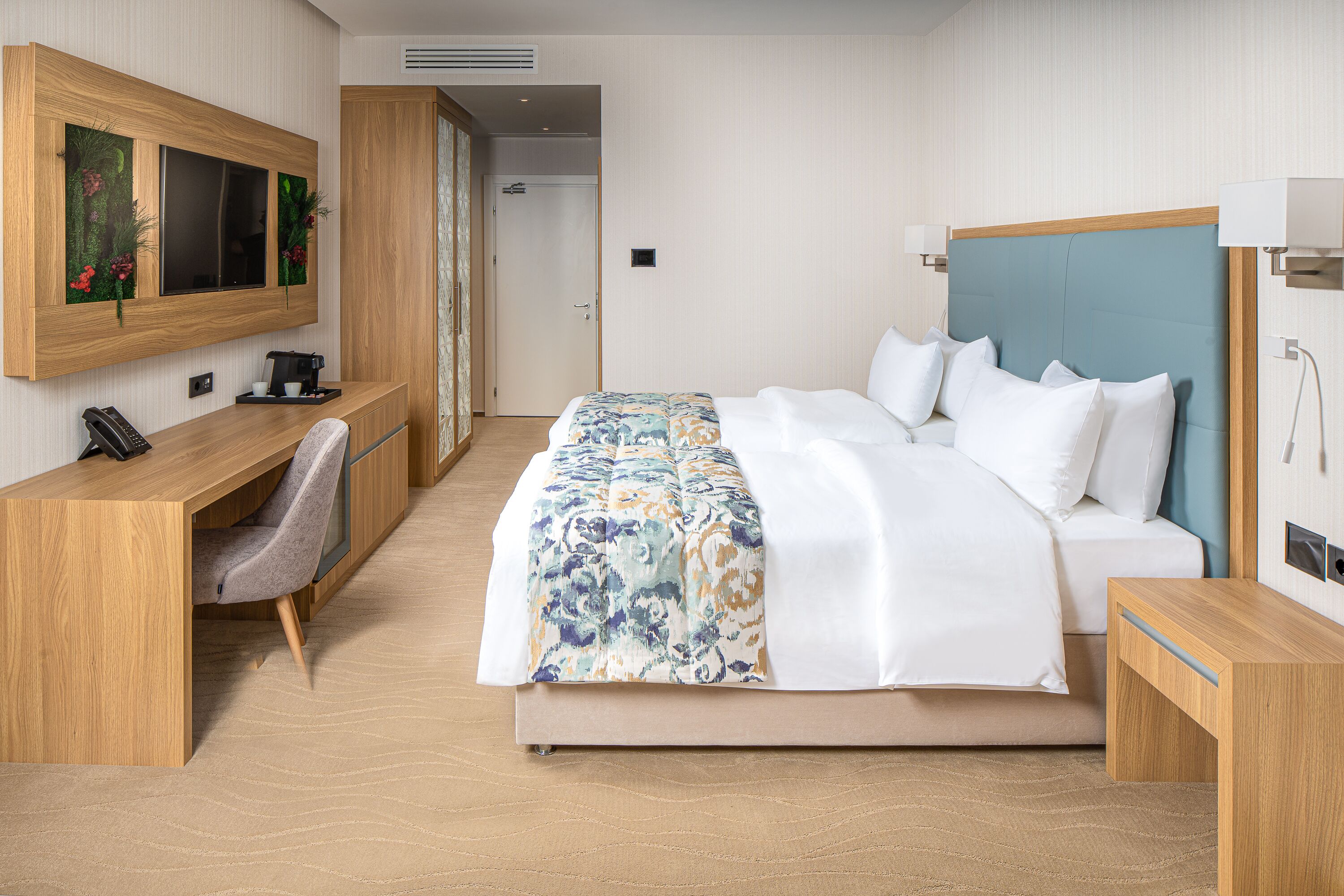 A hotel room with a bed, a desk, a chair, a television, and a bathroom.