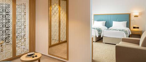 A hotel room with a bed, a sofa, a small table, and a decorative screen.