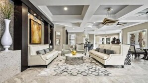 A spacious living room with two sofas, a coffee table, and a dining area with chairs. - Luxury Family Villa in Solterra with Pool, Spa & Games Room Near Disney (Davenport)