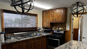 A kitchen with wooden cabinets, a stainless steel sink, a microwave, and a stove. - Drive up & park 6 ft from this clean, equipped houseboat in Cypress Cove Marina (Buras)