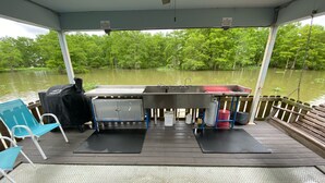 A covered outdoor area with a metal grill, a sink, and a bench. - Drive up & park 6 ft from this clean, equipped houseboat in Cypress Cove Marina (Buras)