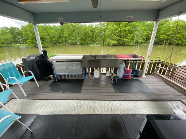 A covered outdoor area with a metal grill, a sink, and a bench.