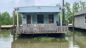 A houseboat with a wooden deck and a covered porch, surrounded by water. - Drive up & park 6 ft from this clean, equipped houseboat in Cypress Cove Marina (Buras)