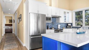 Una cocina moderna con electrodomésticos de acero inoxidable, armarios blancos y una pared azul de acento.