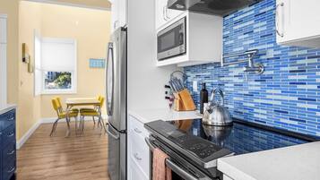 A modern kitchen with a stainless steel refrigerator, a microwave, and a kettle on the counter.