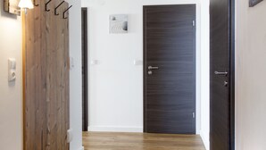 A hallway with wooden flooring, a coat rack, a dark door, and a light fixture on the ceiling. - Stadl Appartements (Tuerkheim)