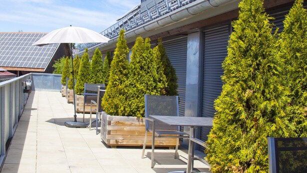 A rooftop terrace with outdoor seating, solar panels, and potted trees. - Stadl Appartements (Tuerkheim)