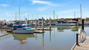 A marina with several boats docked, calm water, and a wooden dock. - Skippers Landing- On the water with private jetty (Lemon Tree Passage)