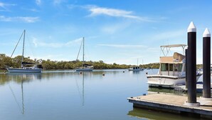 A marina with several boats docked, a dock with a boat named 'MIDWAY', and a calm water body reflecting the sky. - Skippers Landing- On the water with private jetty (Lemon Tree Passage)